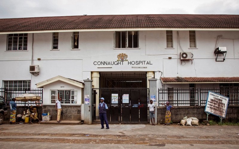 A security guard, center, stands outside the Connaught Hospital, where a leading doctor died from Ebola on Wednesday, in Freetown, Sierra Leone, Friday, Aug. 15, 2014. The Ebola outbreak that has killed more than 1,000 people in West Africa could last another six months, Doctors Without Borders said Friday, and a medical worker acknowledged that the true death toll is unknown. (AP Photo/Michael Duff)