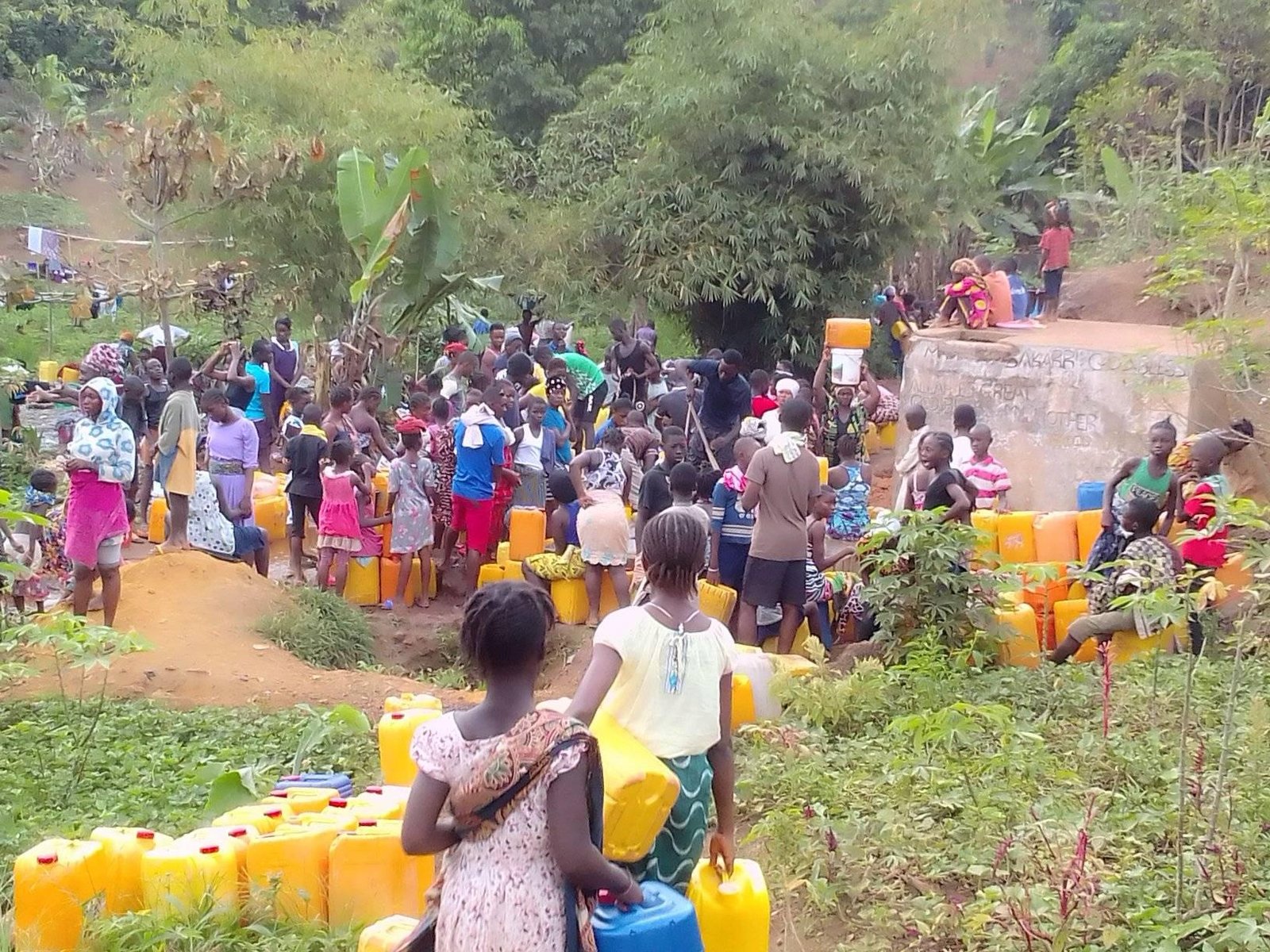 Here are some children and women waiting in-turns to get water at some wells in March at Fourah Bay College Botanical Garden popularly known as botany at Leicester Road community