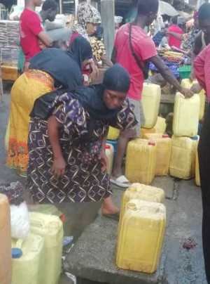 A scene on Fourah Bay Road, Freetown with women struggling to access water on loose rubber pipes